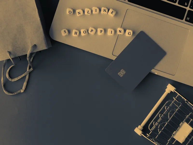 Notebook com cartão e sacola de compras, representando uma loja virtual